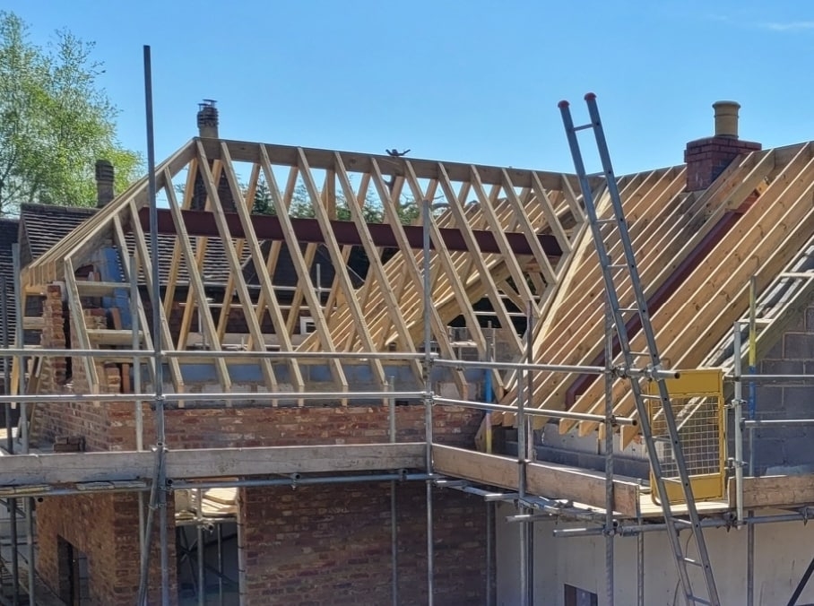 Roof trusses going up on a brick extension with scaffolding