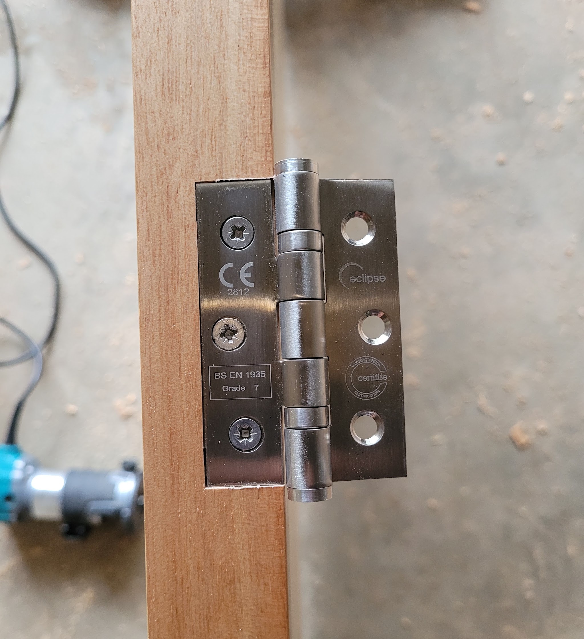 Stainless steel hinge being fitted to a hardwood door