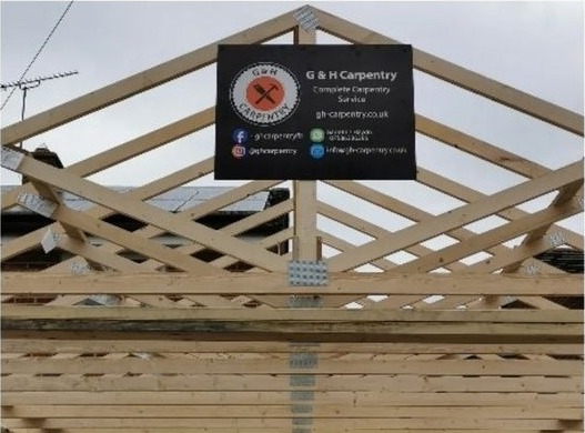 The G & H Carpentry site board on a newly built truss gable